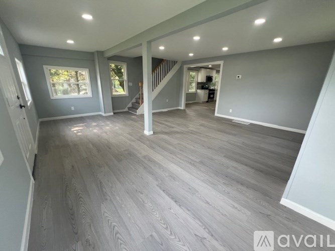 A spacious room with grey flooring and a staircase leading to another room.
