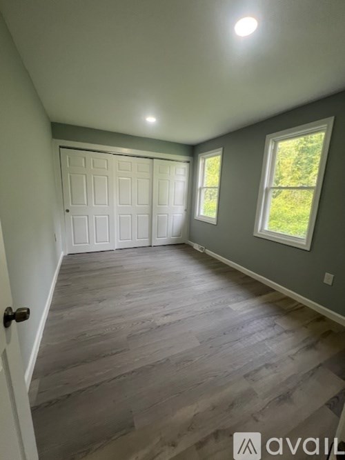 A room with a white door and grey flooring.
