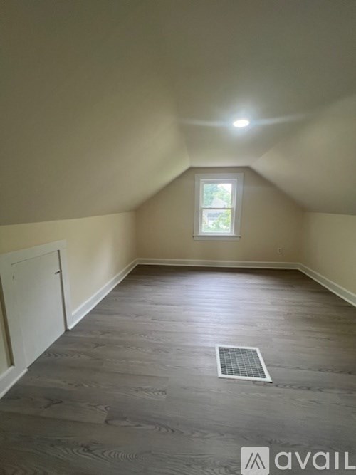 A room with a window and a wooden floor.