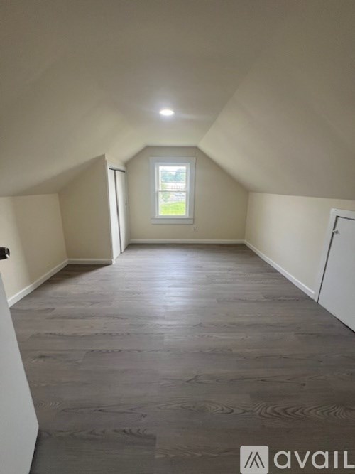 A room with a window and a wooden floor.