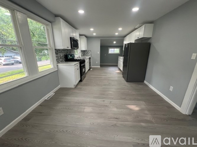 A kitchen with a black refrigerator and white cabinets.