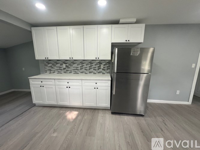A kitchen with white cabinets and a stainless steel refrigerator.