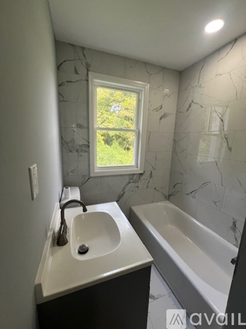 A bathroom with a marble wall and a window.