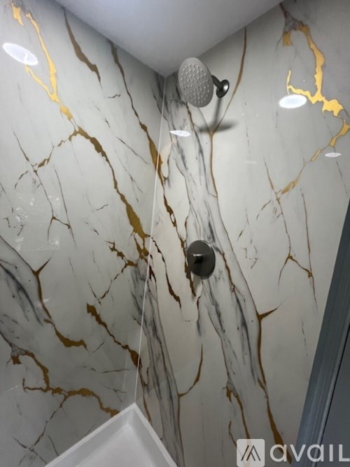 A bathroom with a marble wall and a shower head.