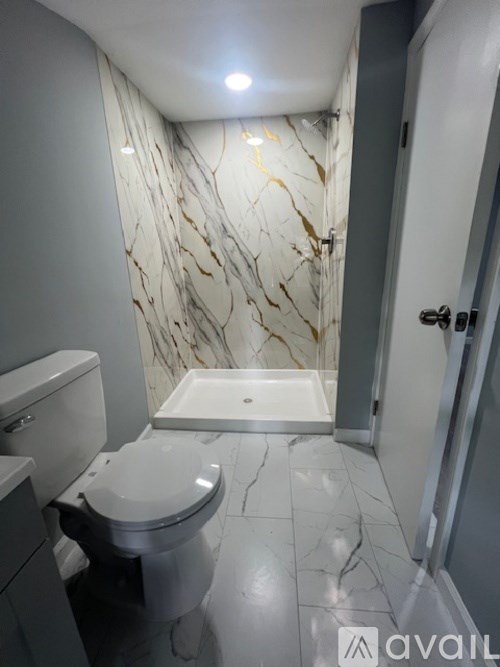 A bathroom with a marble wallpaper and a white toilet.
