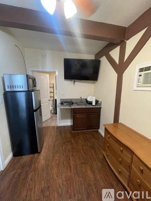 A kitchen with a black fridge and a wooden floor.