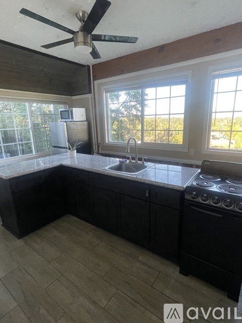 A kitchen with a black stove top oven and a fan on the ceiling.