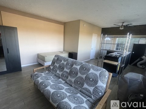 A living room with a grey couch and a fan on the ceiling.