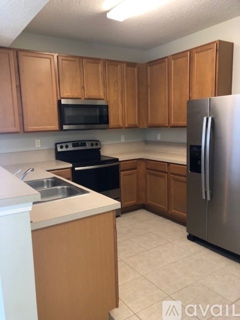 A kitchen with wooden cabinets and a stainless steel refrigerator.