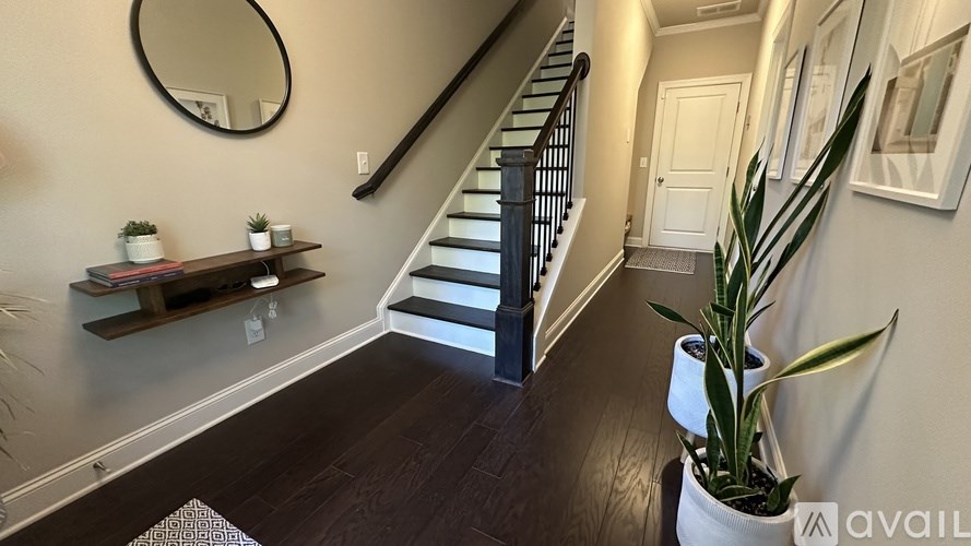 A hallway with a staircase, a mirror, and a plant.