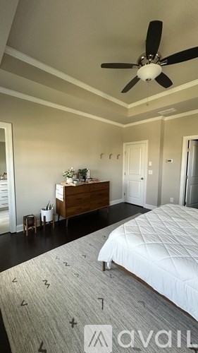 A bedroom with a large bed and a ceiling fan.