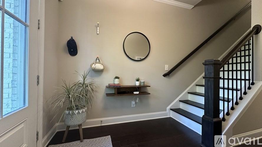 A staircase with a black railing and a round mirror on the wall.