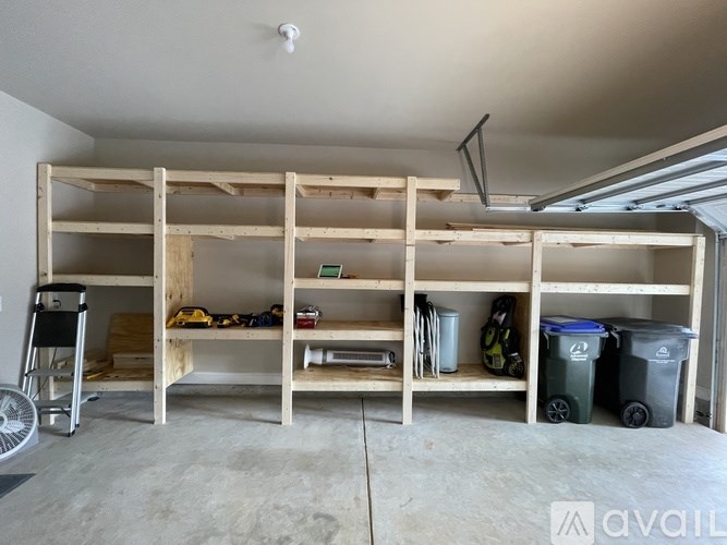 A room with a wooden shelving unit and a fan.