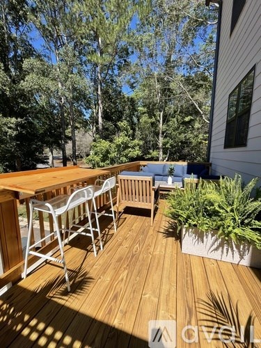 A wooden deck with a table and chairs surrounded by greenery.