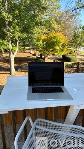 A laptop is sitting on a white table outside.
