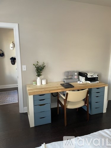 A room with a desk, chair, and a plant.