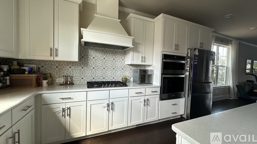 A kitchen with white cabinets and a patterned backsplash.