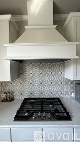 A kitchen with a white stove top and a hood above it.
