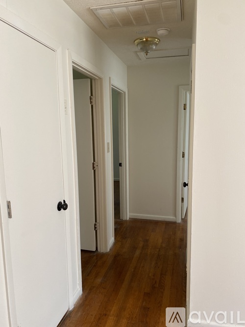 A hallway with a white door and a wooden floor.