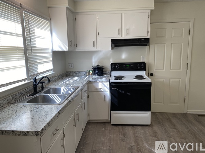 A kitchen with a sink, stove, and cabinets.