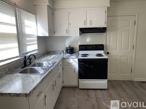 A kitchen with a sink, stove, and cabinets.