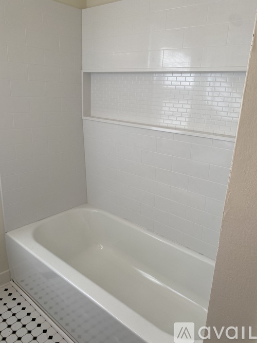 A white bathtub in a bathroom with white tiles.