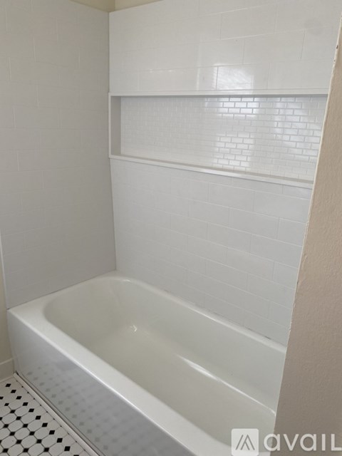 A white bathtub in a bathroom with white tiles.