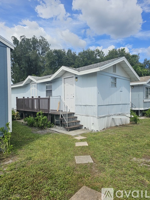 A white mobile home with a deck and a small garden.