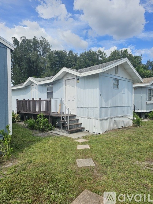 A white mobile home with a deck and a small garden.