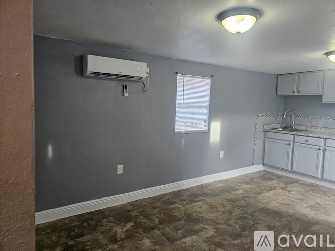 A room with a window, a wall-mounted air conditioner, and a carpeted floor.
