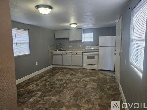 A kitchen with a refrigerator, sink, and cabinets.