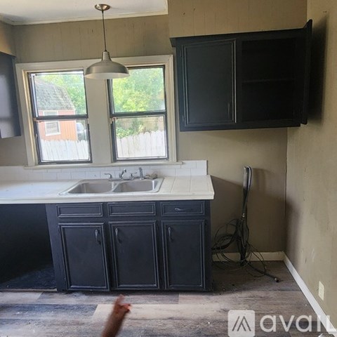 A kitchen with black cabinets and a white sink.