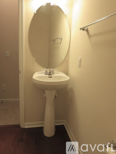 A white pedestal sink with a round mirror above it.