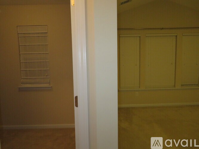 A white door is open to a room with a window and a wall.