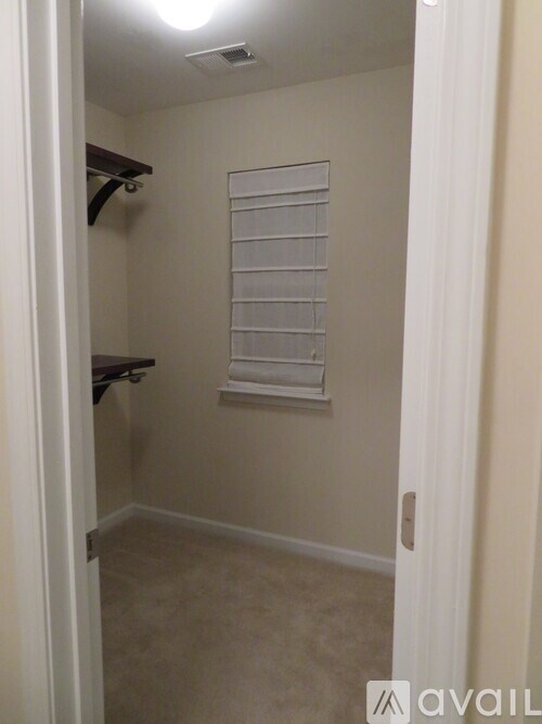 A small, empty room with a window covered by white blinds.