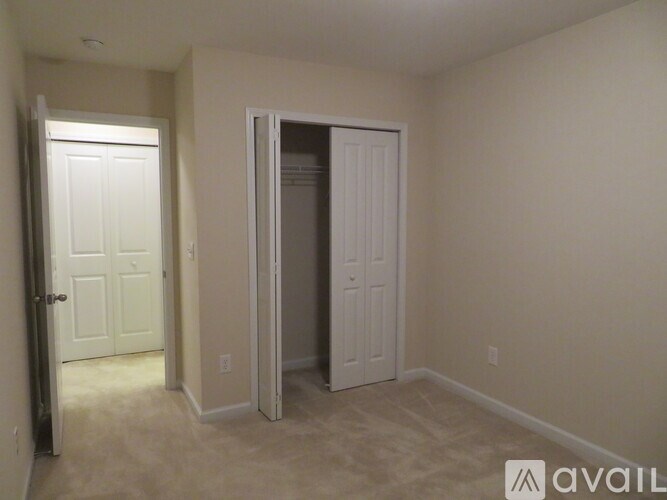 A room with a white door and a carpeted floor.