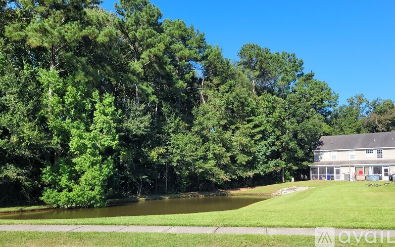 A house is situated by a body of water with trees in the background.