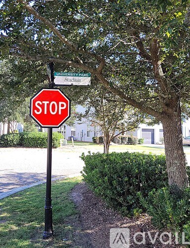 A stop sign is in front of a tree and a sign that says University Park Stadium.