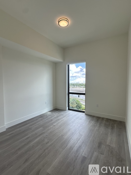 A spacious room with wooden flooring and a sliding glass door leading to a balcony.