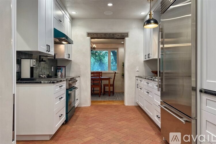 A kitchen with white cabinets and a tile floor.