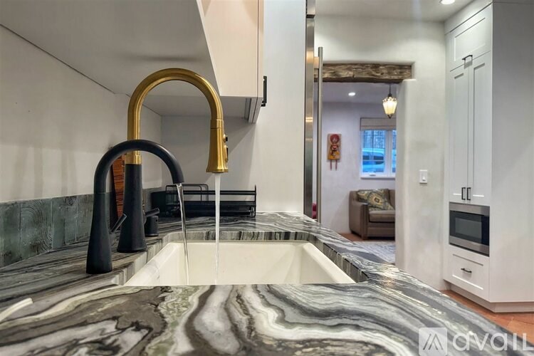 A modern kitchen with a marble countertop and a gold faucet.