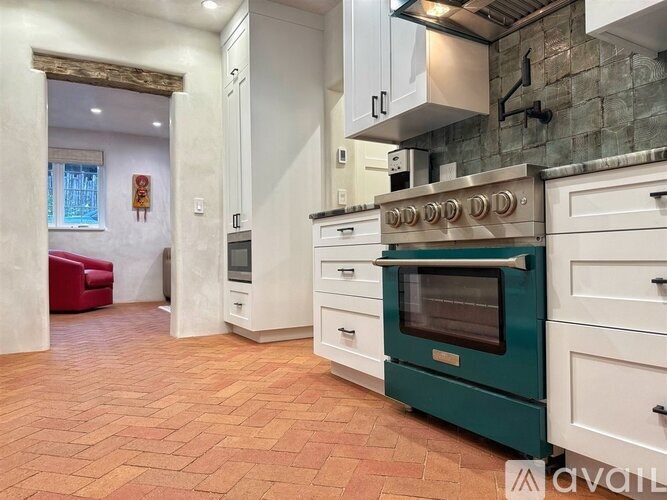 A kitchen with a green oven and white cabinets.