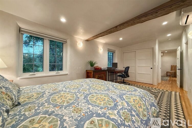 A bedroom with a large bed and a desk with a chair.