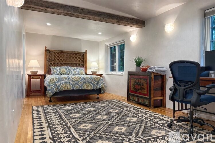 A bedroom with a bed, a chair, and a rug.