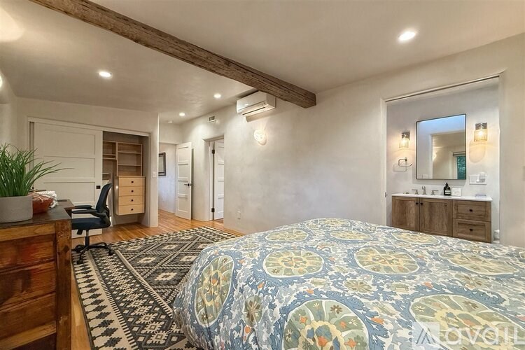 A bedroom with a patterned bedspread and a rug on the floor.