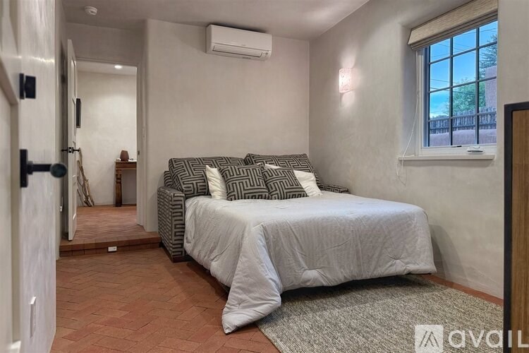 A bedroom with a bed, a window, and a rug.