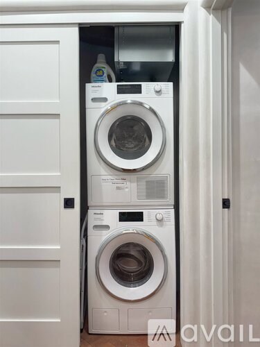 A white washing machine is in a cabinet.