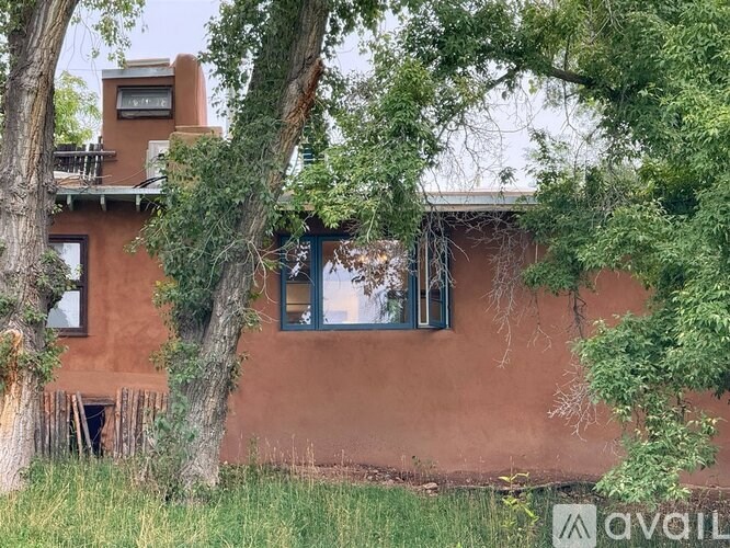 A house with a balcony and a tree in front of it.