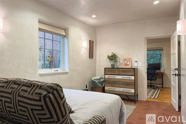 A bedroom with a bed, a dresser, and a window.