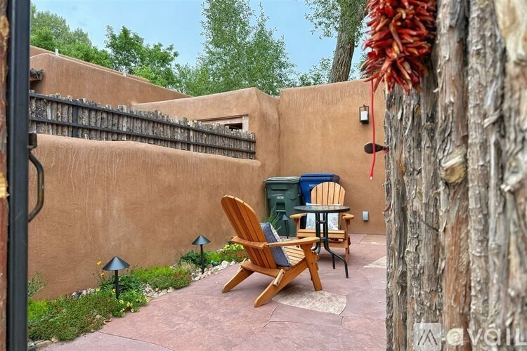 A patio with a table and chairs is surrounded by a wall and trees.